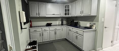 A modern kitchen with white cabinets, a black countertop, and a tiled floor.