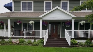 A two-story house with a front porch, a staircase leading to the entrance, and a well-maintained lawn.