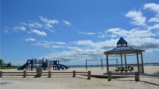 A beach with a playground, including slides and a gazebo.