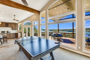 Amplio espacio interior con mesa de ping pong, armarios de madera y ventanas grandes que dan al exterior.