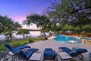 Un área de piscina con sillones de descanso y vistas a un lago.