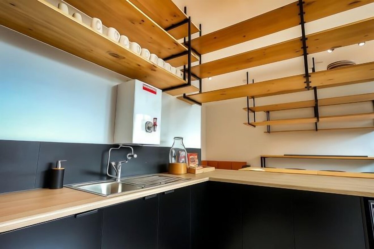 Una cocina moderna con armarios negros, una encimera de madera y un estante empotrado sobre el fregadero.