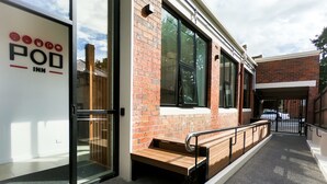 A modern building with a glass entrance, a wooden bench outside, and a brick facade. - Pod Inn (Launceston)