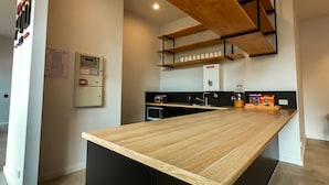 A modern kitchen with a wooden countertop, black cabinets, and a built-in microwave. - Pod Inn (Launceston)