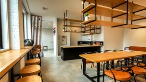 A modern cafe with wooden tables and chairs, a kitchen area, and a brick wall. - Pod Inn (Launceston)