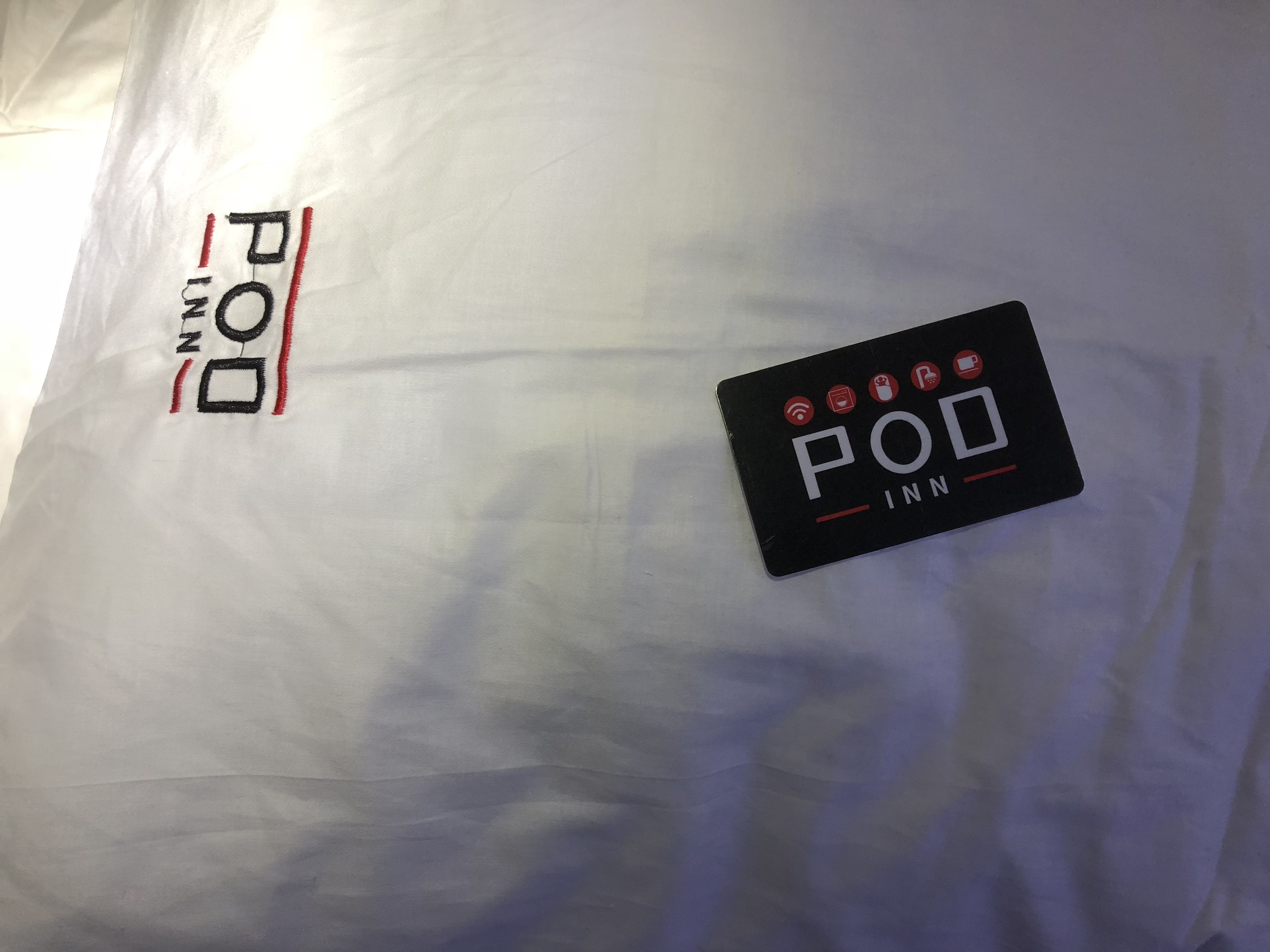 A black sign with the text "POU INN" and icons indicating amenities such as Wi-Fi, a bed, a bathroom, and a TV.