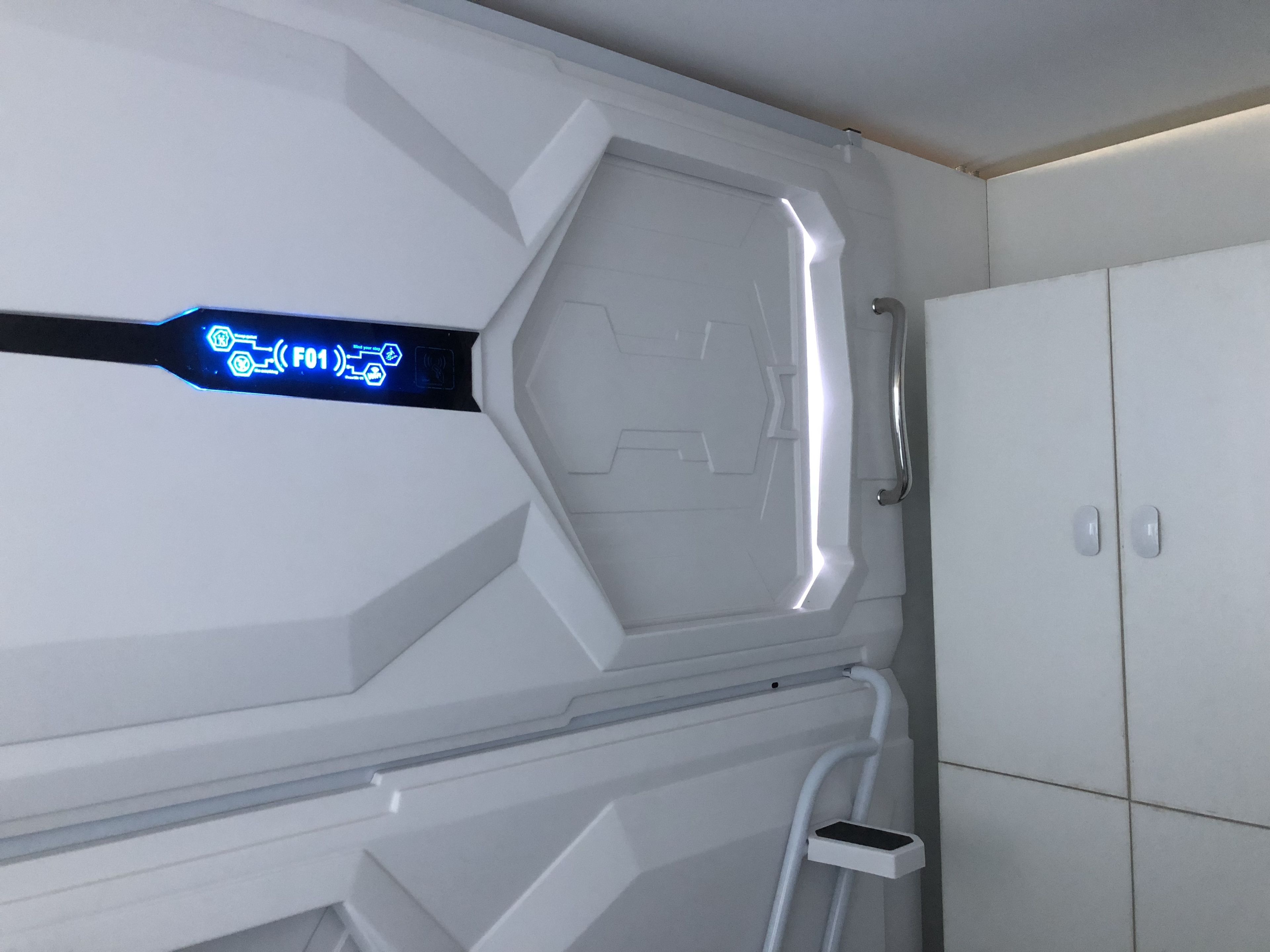 A futuristic room with a control panel displaying 'F01' and a metallic handle.