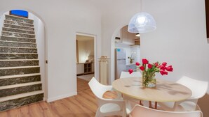 A modern kitchen with white cabinets, a refrigerator, and a dining area with a round table and white chairs.