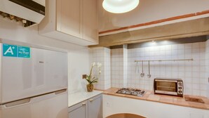 A compact kitchen with a white refrigerator, a gas stove, a toaster, and a small sink.