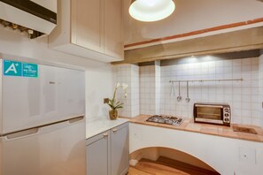 A compact kitchen with a white refrigerator, a gas stove, a toaster, and a small sink.