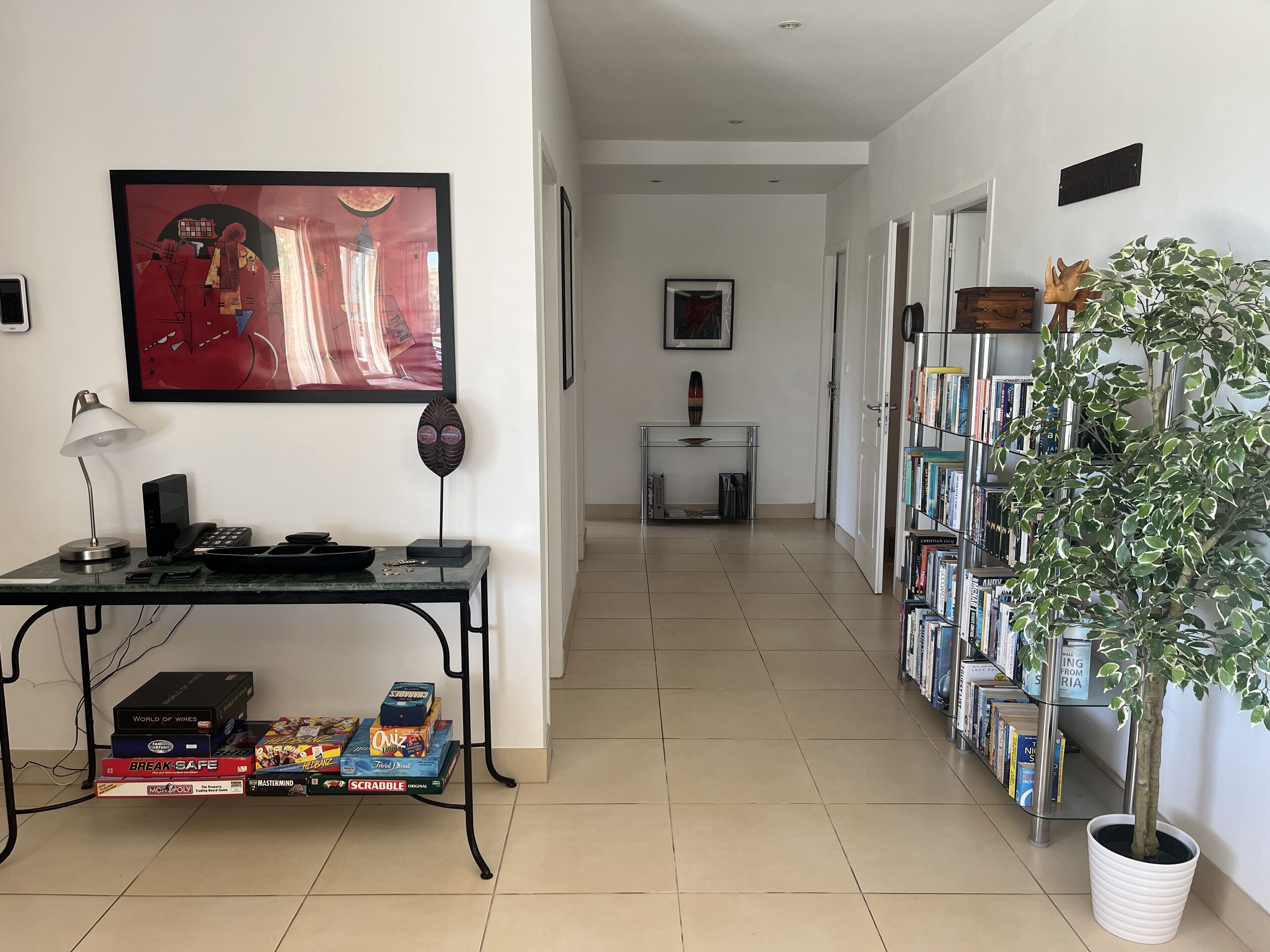 Un couloir avec un bureau, une bibliothèque et une plante en pot.