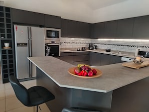 A modern kitchen with a central island, built-in appliances, and a black-framed refrigerator. - Secluded, Exclusive spacious villa with private heated pool, full air-con, Wi-Fi (Azille)
