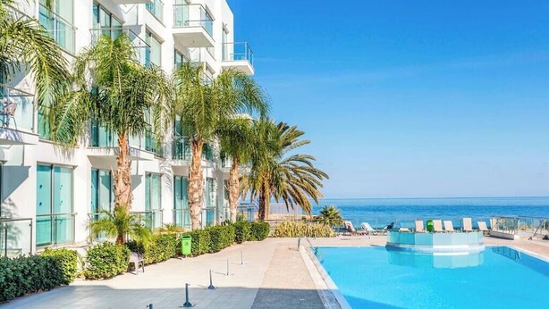 Ein modernes Hotel mit Pool, Palmen und Meerblick.
