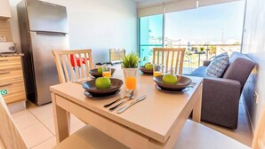 Eine moderne Küche mit Kühlschrank, Esstisch gedeckt mit Tellern, Äpfeln und Gläsern Orangensaft.