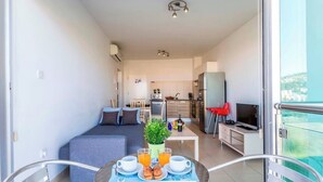 Eine moderne Wohnung mit Balkon, einer Essecke mit Frühstück, einer Küche und einem Wohnzimmer.