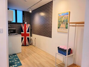 A modern kitchen with a black brick backsplash, a Union Jack flag, and a framed Claude Monet painting. - Gallery Family Hotel (Mokpo)