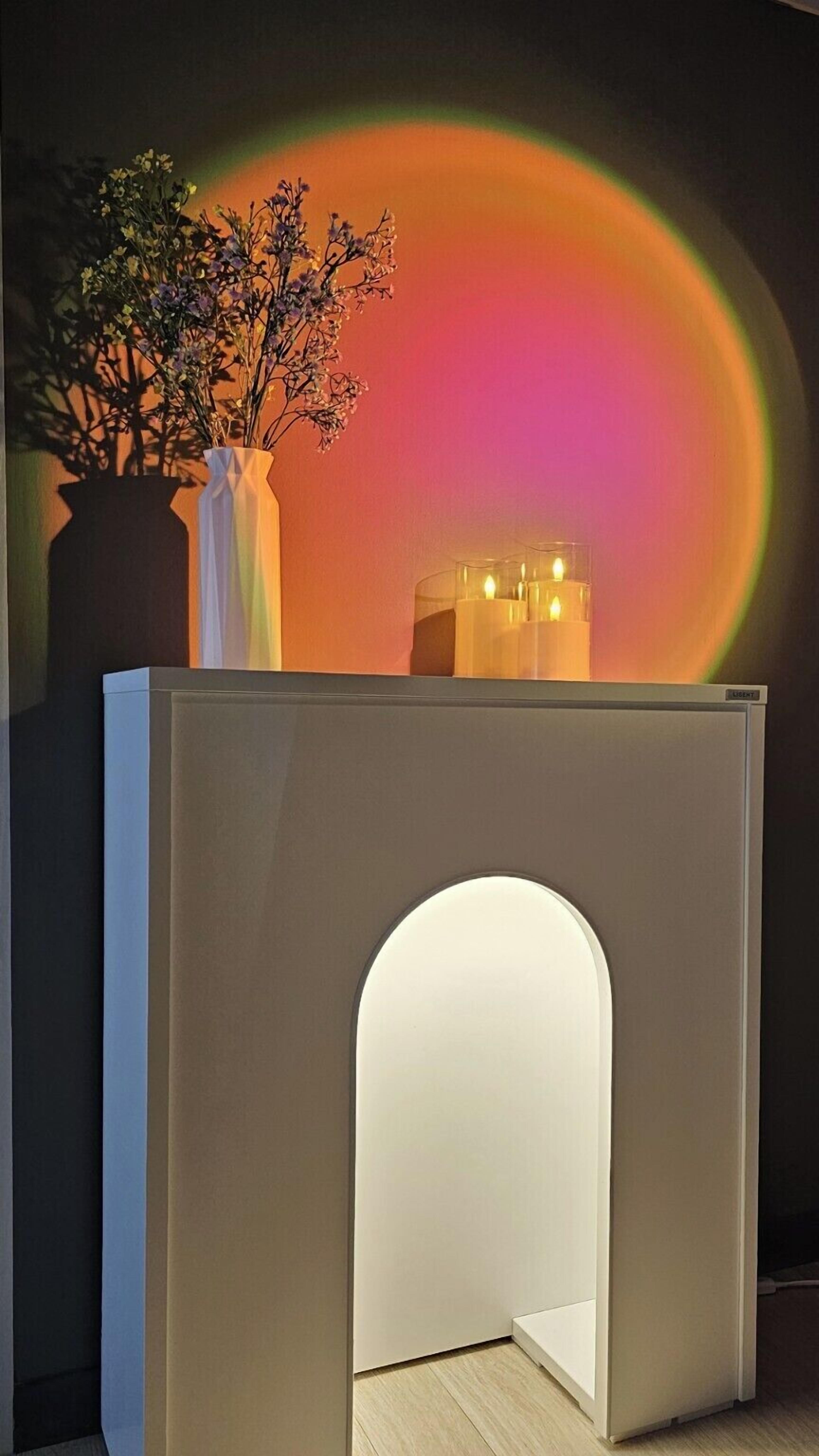 Una habitación moderna con un diseño minimalista, que presenta un tocador blanco con un arco empotrado, una planta en maceta y una lámpara fijada a la pared.