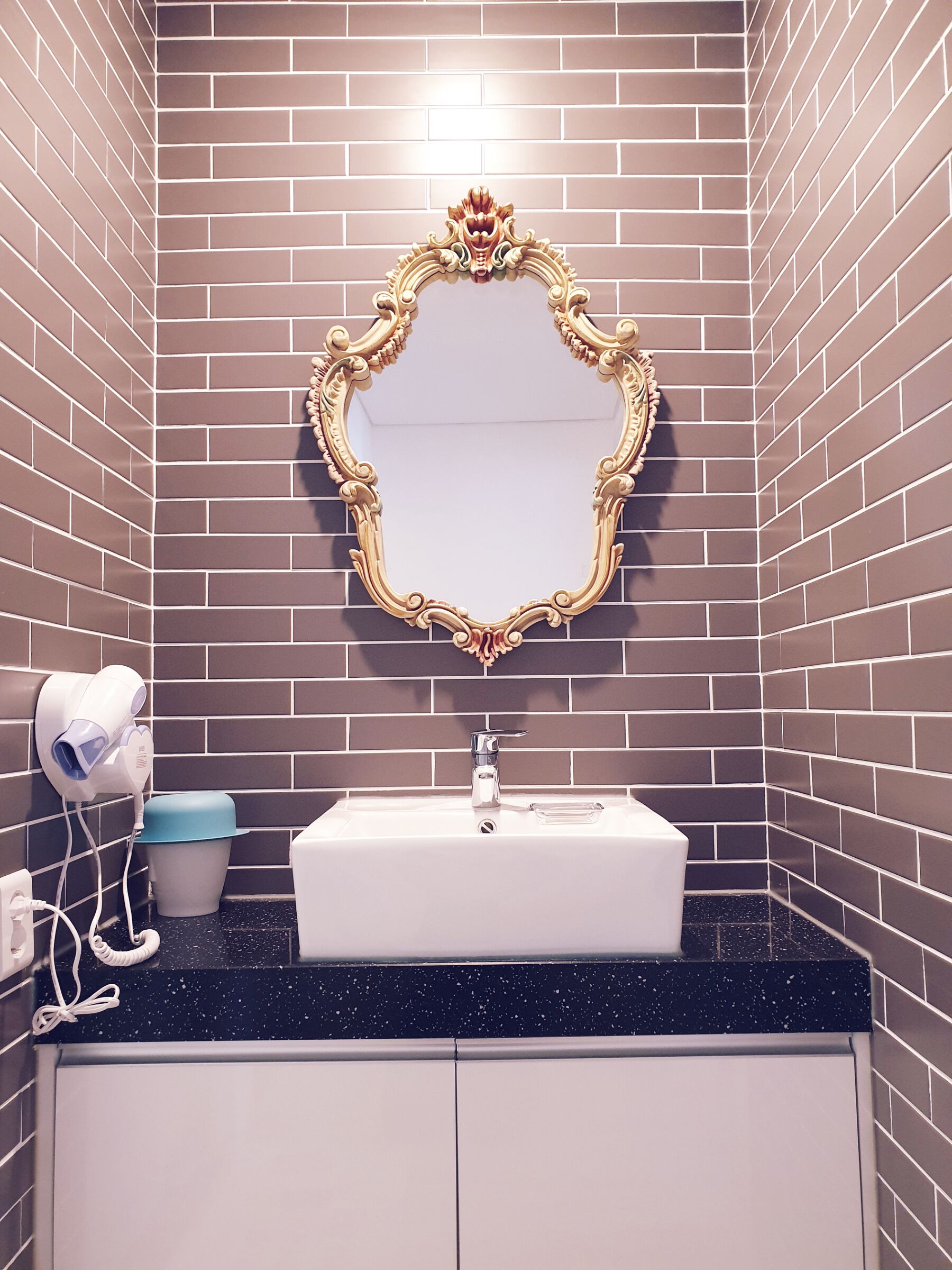 A bathroom with a mirror, sink, and hairdryer.