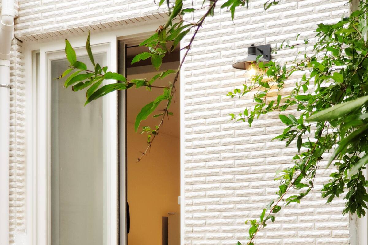 A room with a white brick wall, a sliding glass door, and a wooden bench outside.