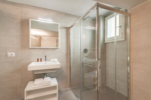 Une salle de bain moderne avec une douche à parois de verre, un lavabo blanc et un miroir au-dessus.