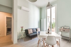 Un salon moderne avec un canapé, une table à manger et des chaises, un radiateur et une vue sur l’extérieur.