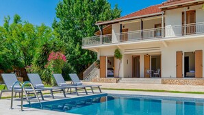 Une maison à deux étages avec une piscine, un espace salon extérieur et un jardin.
