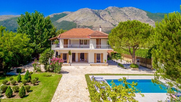Une maison à deux étages dotée d’un balcon, d’une piscine et surplombant un paysage montagneux.
