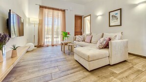 Un salon moderne avec un canapé, un téléviseur, une lampe et une plante.