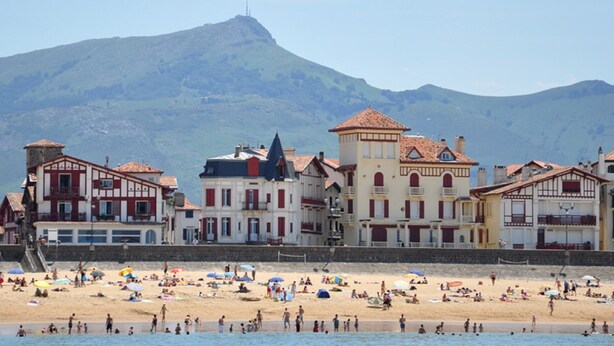 Ein Strand mit Gebäuden im Hintergrund und einem Berg.