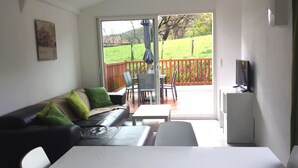 Ein Wohnzimmer mit Sofa, Sesseln, Couchtisch und Fernseher.