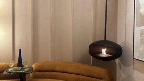Ein modernes Interieur mit einer Couch, einem Tisch mit Gläsern und einer Flasche sowie einer Pendelleuchte.