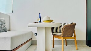 Ein modernes Wohnzimmer mit einer Couch, einem Esstisch und einem Korbstuhl.