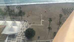 Ein Strand mit Palmen, einem Weg und einem Gebäude mit Ziegeldach.
