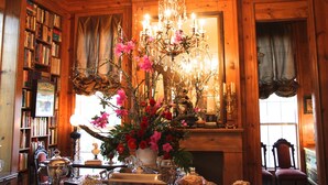 A wooden-paneled room with a chandelier, a fireplace, and a bookshelf filled with books. - Sunnyside Bed & Breakfast (Natchez)