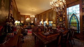 A cozy library with a large wooden bookcase, a stained glass window, and a chandelier. - Sunnyside Bed & Breakfast (Natchez)