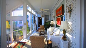 A bright, sunlit room with a ceiling fan, a sofa, a chair, and a small table with a lamp. - Sunnyside Bed & Breakfast (Natchez)