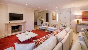 Een ruime woonkamer met een open haard, een televisie en een rood tapijt.