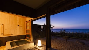 A wooden spa area with a hot tub and a view of the beach at dusk. - Yusai Resort HIBIKI (Kyotango)