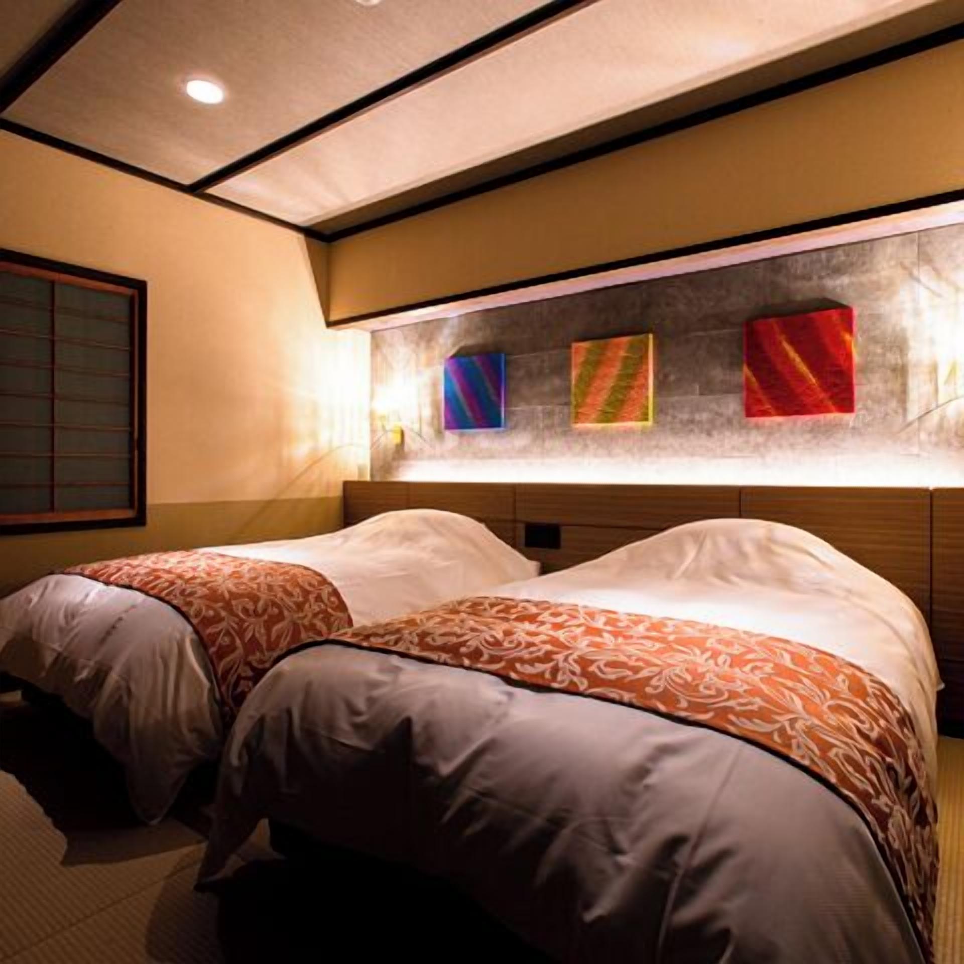 Une chambre d’hôtel avec deux lits, une tête de lit en bois et trois œuvres d’art colorées accrochées au mur.