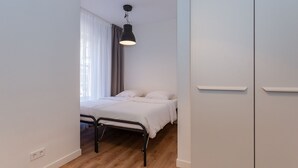 Une chambre à coucher avec un lit, un luminaire suspendu, une fenêtre avec des rideaux et une armoire.