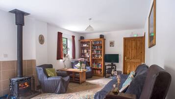 Un salon chaleureux avec une cheminée, une bibliothèque et des sièges confortables.