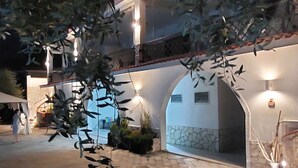 A multi-story building with a stone facade, arched doorways, and outdoor lighting. - Brand new apartment with veranda (Peschici)