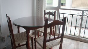 Un coin repas avec une table ronde et quatre chaises en bois dont les assises sont en osier tressé.