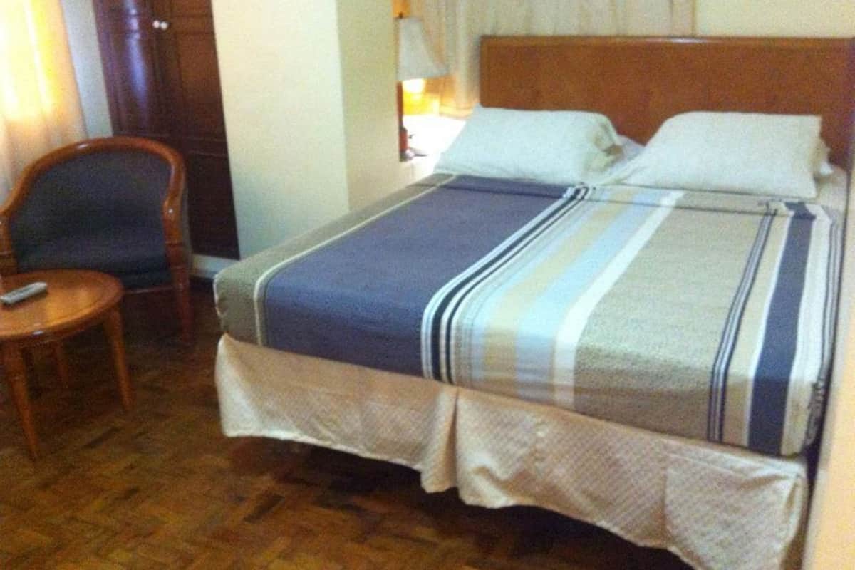 Ein Hotelzimmer mit einem hölzernen Bett, einem kleinen runden Tisch und einem Stuhl.