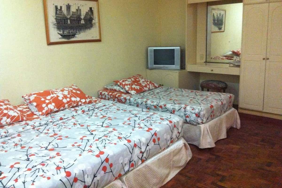 Ein Zimmer mit zwei Betten, einem Fernseher und einem Schrank.