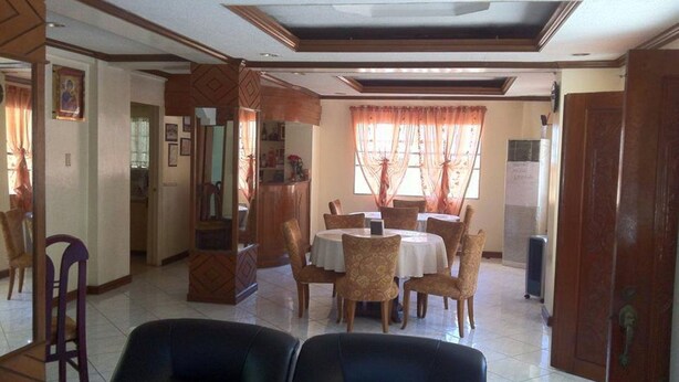 A dining area with a round table and chairs, a bar area, and a reception desk. - Tondaligan Beach Hotel (Dagupan)