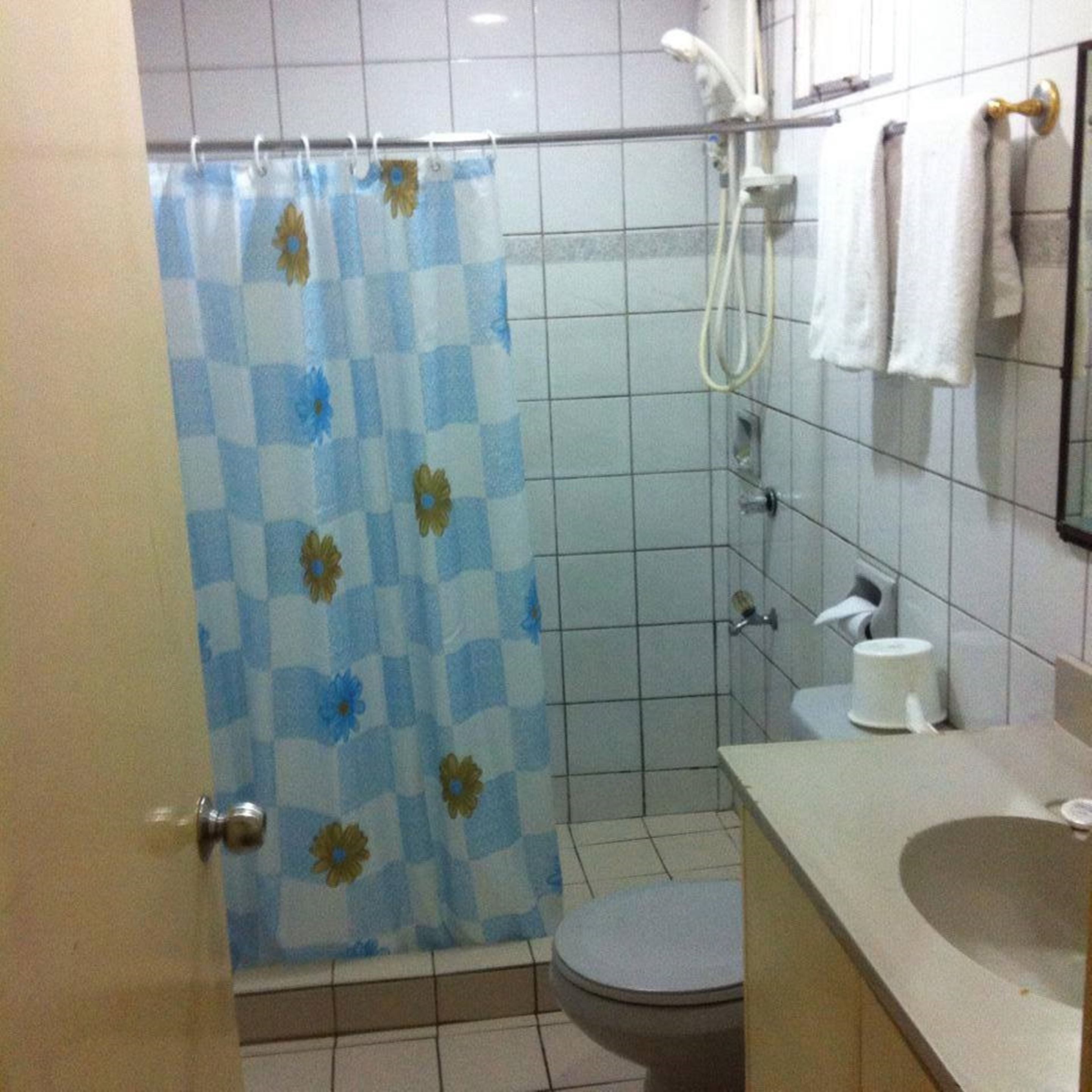 A bathroom with a shower curtain, a toilet, a sink, and a towel rack.