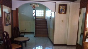 A hallway with a staircase, a dining area with chairs and a table, and a framed picture on the wall. - Tondaligan Beach Hotel (Dagupan)