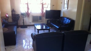 A living room with a black sofa, a coffee table, and a TV. - Tondaligan Beach Hotel (Dagupan)