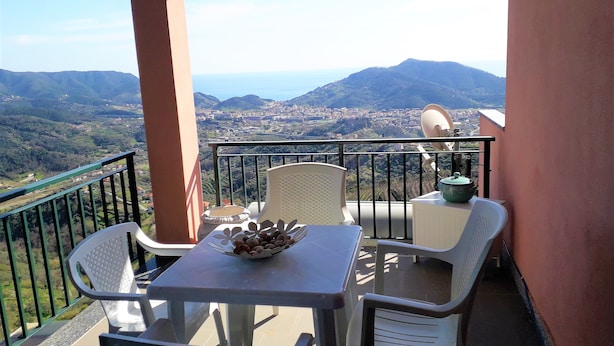 Ein Balkon mit Tisch und Stühlen, einer Obstschale und einer Satellitenschüssel.